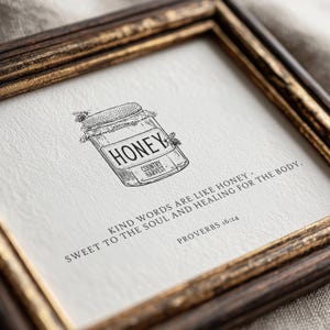 May include: A square framed print featuring a black ink illustration of a honey jar with two bees. The text reads HONEY COUNTRY HARVEST and KIND WORDS ARE LIKE HONEY - SWEET TO THE SOUL AND HEALING FOR THE BODY. PROVERBS 16:24 on white paper.
