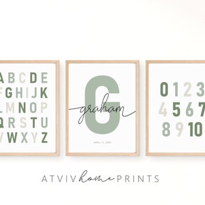 May include: Three framed prints with a green and beige color scheme. The first print features the alphabet in a grid pattern. The second print features the letter "G" in a large font with the name "graham" written in cursive below. The third print features the numbers 0-10 in a grid pattern.