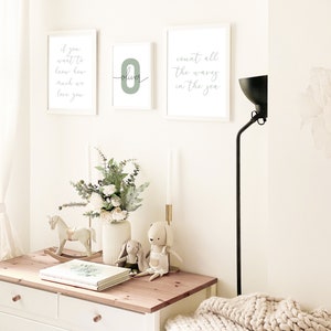 May include: Three white framed prints on a white wall. The left print says "If you want to know how much we love you". The middle print has a green number "0" with the name "Oliver" written in cursive. The right print says "Count all the waves in the sea".