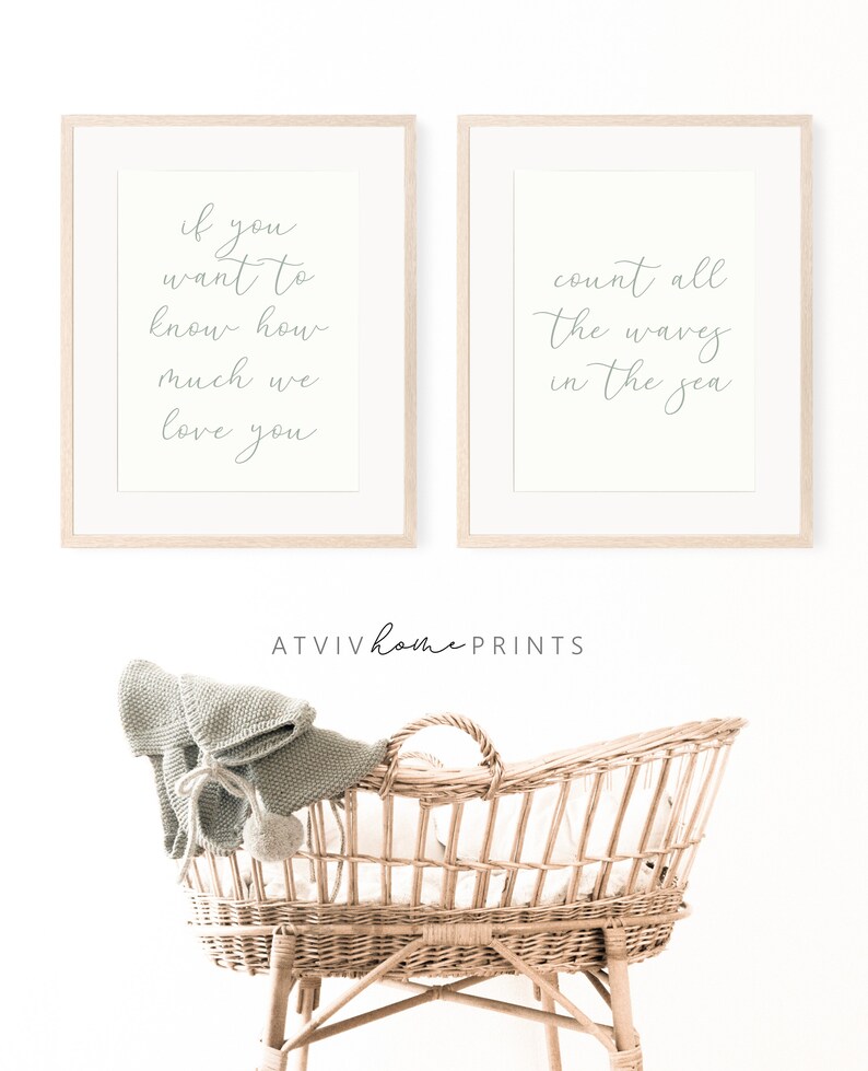 May include: Two framed prints with white backgrounds and grey text. The left print reads "if you want to know how much we love you". The right print reads "count all the waves in the sea". A wicker bassinet with a light green knitted blanket is in the foreground.