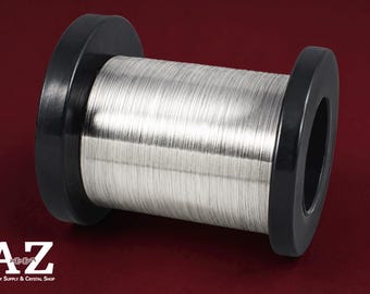 May include: A spool of thin, metallic silver-coloured wire wound tightly around a black cylindrical core. The wire has a smooth, reflective finish and is evenly distributed across the length of the spool. The text A-Z Jewelry Supply & Crystal Shop is visible in the bottom left corner.