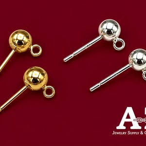 May include: Four metal earring posts with ball studs and attached loops for jewelry making. Two posts are gold-toned and two are silver-toned. The text A-Z Jewelry Supply & Crystal Shop is visible in the bottom right corner.