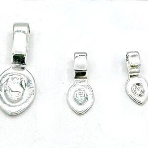 May include: Three silver-toned metal bead caps in different sizes. The caps are shaped like teardrops with a small loop at the top.