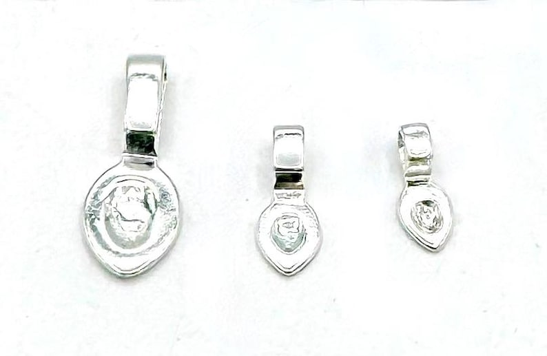 May include: Three silver-toned metal bead caps in different sizes. The caps are shaped like teardrops with a small loop at the top.