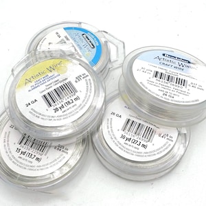 May include: Several spools of Artistic Wire craft wire in clear plastic containers. The spools are labeled with gauge sizes, wire lengths, and other details. The wire appears to be silver-colored and is intended for craft projects.