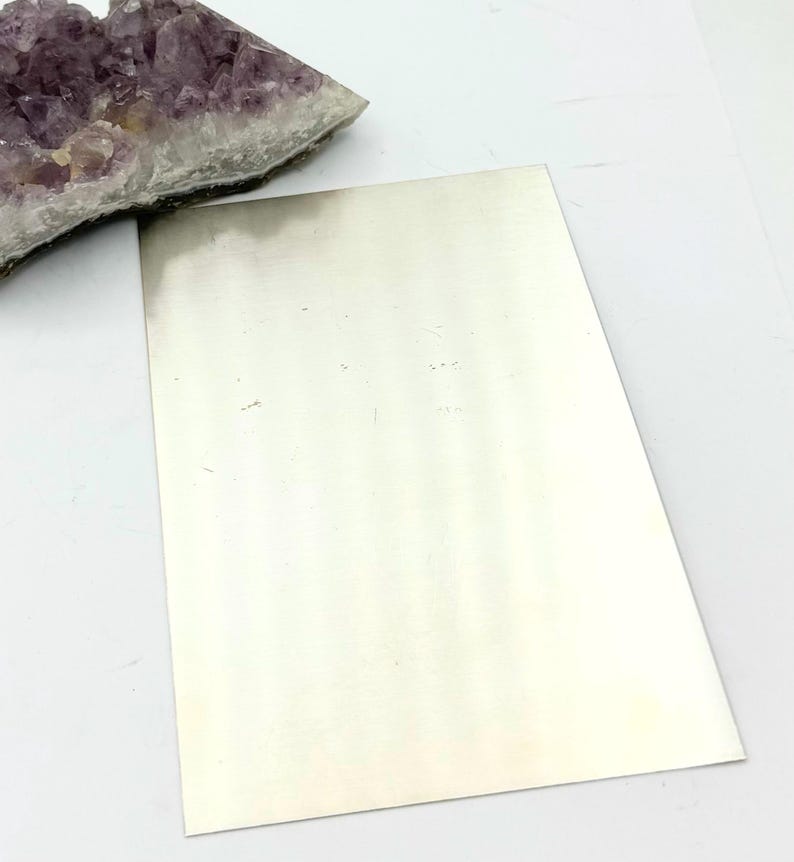 Puede incluir: Una l&aacute;mina de metal plateado, con una superficie lisa y brillante.