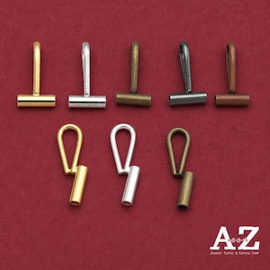 May include: A collection of eight metal jewelry bails in various finishes including gold, silver, bronze, gunmetal, and copper. The top row features five T-shaped bails, while the bottom row displays three loop-style bails with cylindrical ends.