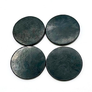 May include: Four round black coasters with a slightly textured surface.