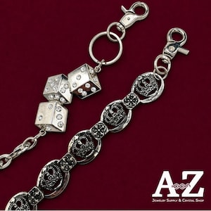 Peut inclure: Deux chaînes en métal argenté avec fermoirs mousquetons. L'une comporte deux dés ornés de strass transparents. L'autre est composée de maillons en forme de couronne et de croix. Le texte A-Z Jewelry Supply & Crystal Shop est présent.