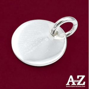 May include: A circular silver pendant featuring a smooth, reflective surface and a small attached jump ring at the top. The pendant has a polished metallic finish. In the bottom right corner, the text reads A-Z Jewelry Supply & Crystal Shop.