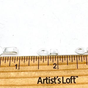 May include: Close-up of five clear plastic clasps for jewelry making, measured on a ruler with the text "Artist's Loft" in inches.