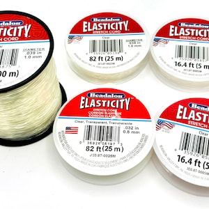 May include: Four spools of clear elastic stretch cord for jewelry making. The spools are labeled with the brand name Beadalon and the length of the cord in feet and meters. The cord diameters are 0.032 inches and 0.039 inches.