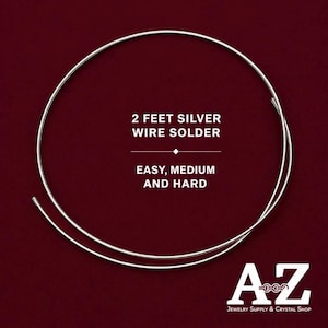 Puede incluir: Una bobina circular de hilo de soldadura de plata con el texto 2 FEET SILVER WIRE SOLDER EASY, MEDIUM AND HARD. La esquina inferior derecha presenta un logotipo con las letras A y Z y el texto Jewelry Supply & Crystal Shop.