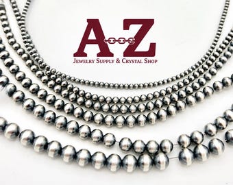 May include: Five strands of metallic silver-coloured round beads arranged in a semi-circle. The beads vary in size across the strands. The text A-Z Jewelry Supply & Crystal Shop is centred above the beads in dark red lettering.