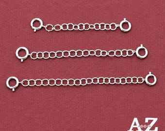 May include: Three silver-toned metal jewelry extender chains of varying lengths, each featuring a circular spring ring clasp at both ends. The chains consist of interconnected round links, arranged horizontally from shortest to longest.