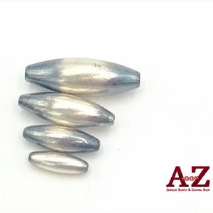 May include: Four elongated, spindle-shaped beads with a metallic silver finish and a smooth, reflective surface. The beads are arranged vertically by size, from largest to smallest, and feature a logo in the bottom right corner reading A-Z Jewelry Supply & Crystal Shop.