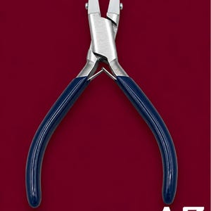 May include: Metal pliers featuring flat, white nylon-coated jaws and a silver-toned steel body. The handles are covered in smooth, dark blue rubberized grips. A small metal spring is positioned between the handles. The text AZ is visible.