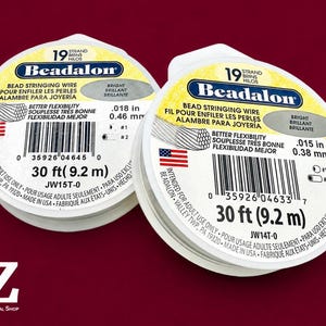 May include: Two round spools of Beadalon 19-strand bead stringing wire. The left spool is labeled .018 in (0.46 mm) and the right spool is labeled .015 in (0.38 mm). Both spools contain 30 ft (9.2 m) of wire and feature a white label with black text.