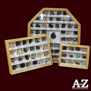 May include: Three wooden display cases containing various small mineral specimens and crystals. Each compartment features a white label with the name of the stone. The collection includes labeled samples like ammonite, jasper, quartz, and calcite.