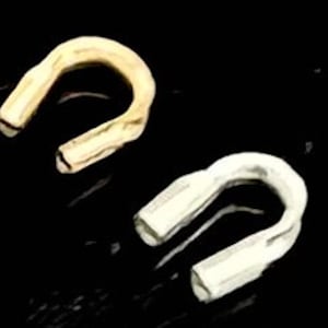 May include: Two metal jump rings, one gold and one silver, with a textured finish. The rings are open and have a U-shape.