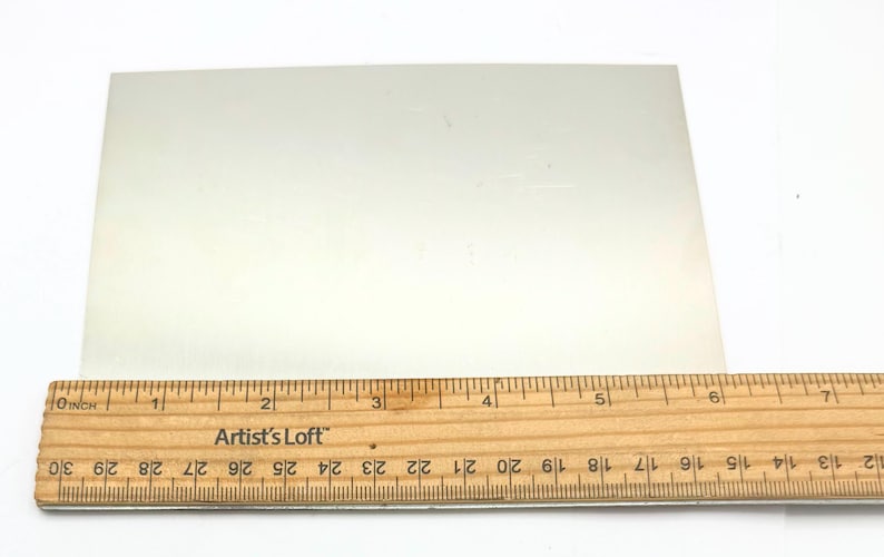 Puede incluir: Una l&aacute;mina de metal rectangular blanca que mide 15,2 cm por 10,2 cm. La l&aacute;mina de metal es lisa y tiene un ligero brillo.