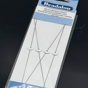 May include: A package of Beadalon big eye beading needles. The package is white and blue, with the text "Beadalon" and "BIG EYE BEADING NEEDLE" printed on it. The package contains four fine needles, each with a large eye.