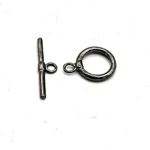 May include: A black metal toggle clasp with a round ring and a straight bar. The clasp is used for jewelry making.