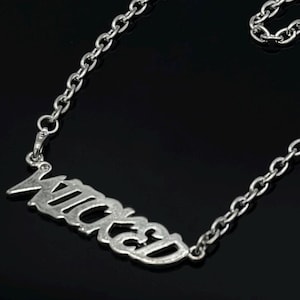 Puede incluir: Un collar de plata con un colgante que dice "Wicked" en una fuente estilizada.