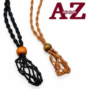 May include: Two macrame stone holders on braided cords, one black and one tan, each featuring a single wooden bead above a knotted net pouch. The text A-Z is displayed in dark red letters in the upper right corner of the image.