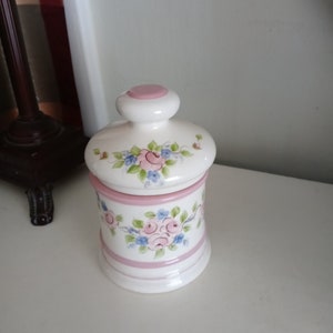 Op de afbeelding: Een witte keramische mok met een zwart handvat en de tekst "But First, Coffee" in een vetgedrukte, zwarte letter. De mok staat op een houten oppervlak. De mok is ongeveer 10 cm hoog.