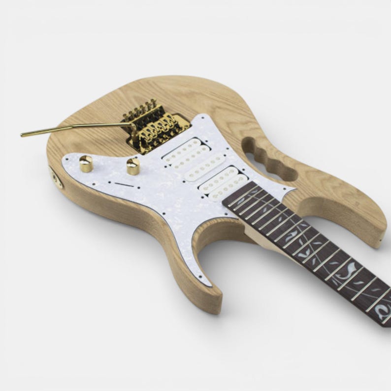 Unfinished natural wood electric guitar body of Ibanez Jem guitar with a white pickguard and gold hardware assembled. The guitar has a tremolo bridge and a single output jack.