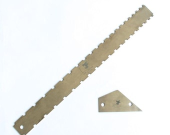 Könnte beinhalten: Ein Set aus zwei Holzwerkzeugen, ein langes Lineal mit gezackten Kanten und ein kleines dreieckiges Stück. Beide Werkzeuge sind hellbraun und tragen den Aufdruck "The Yellow Caliper". Das Lineal hat ein Loch an einem Ende.