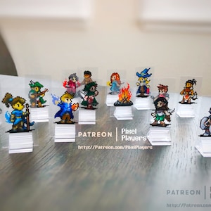 May include: A set of 12 pixel art character figurines on clear acrylic stands. The characters are in various poses and include a wizard, a warrior, a rogue, and a cleric. The figurines are all brightly colored and detailed. The text "PATREON | Pixel Players" and a website address are printed on the stands.