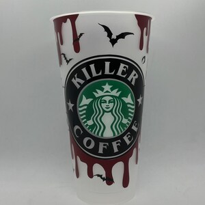 May include: White reusable cup with a red dripping blood design. The cup has a black and white graphic of a Starbucks logo with the text "Killer Coffee" around it. There are also black bats on the cup.