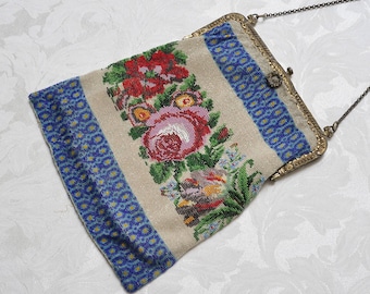 May include: A vintage beaded purse with a floral design in shades of pink, red, green, and blue. The purse has a metal frame and a chain strap.