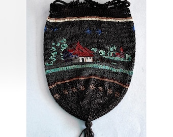 Puede incluir: Una bolsa de cordón negro con cuentas con una escena colorida de una casa y árboles. La bolsa tiene un largo borla negro.