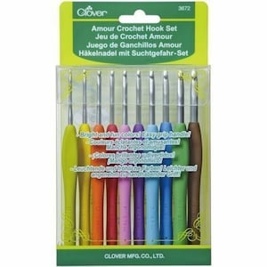 May include: A set of 10 colorful crochet hooks with easy grip handles. The hooks are labeled with sizes from B to I. The packaging is green and features the Clover logo and the text "Amour Crochet Hook Set".