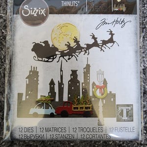 May include: A Sizzix Thinlits die set featuring a cityscape with Santa Claus flying over the city in his sleigh pulled by reindeer. The die set includes 12 dies, 12 matrices, 12 troqueles, 12 fustelle, 12 вырубки, 12 stanzen, and 12 cortantes. The die set is designed by Jim Holtz.