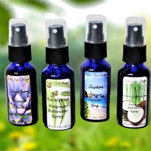 May include: Four blue glass bottles with spray tops and labels. The labels have images of plants and text that reads "Citron Agave Potpourri Refresher Spray", "Eucalyptus Potpourri Refresher Spray", "Seashore Potpourri Refresher Spray", and "Coconut Lemongrass Potpourri Refresher Spray".