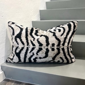 Könnte beinhalten: Schwarz-weiß gemustertes Kissen mit weicher, plüschiger Textur. Das Kissen ist aus luxuriösem Samtstoff gefertigt und hat ein kühnes, abstraktes Design.