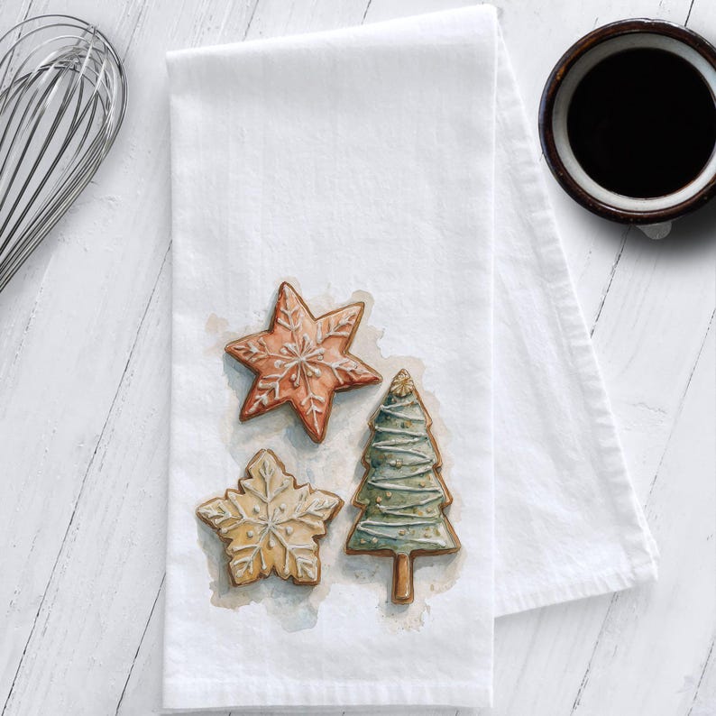 White cotton flour sack tea towel featuring watercolor art of decorated Christmas cookies – star, snowflake, and Christmas tree