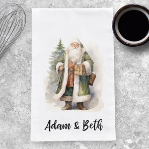 May include: A watercolor illustration of Santa Claus holding a gift, standing in front of a Christmas tree. The text "Adam & Beth" is printed below the image.