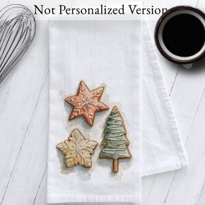 White cotton flour sack tea towel featuring watercolor art of decorated Christmas cookies – star, snowflake, and Christmas tree
