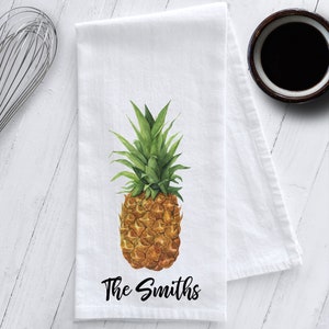May include: White kitchen towel with a watercolor illustration of a pineapple and the text "The Smiths" in black.