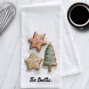 White cotton flour sack tea towel featuring watercolor art of decorated Christmas cookies – star, snowflake, and Christmas tree