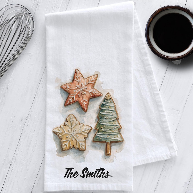 White cotton flour sack tea towel featuring watercolor art of decorated Christmas cookies – star, snowflake, and Christmas tree