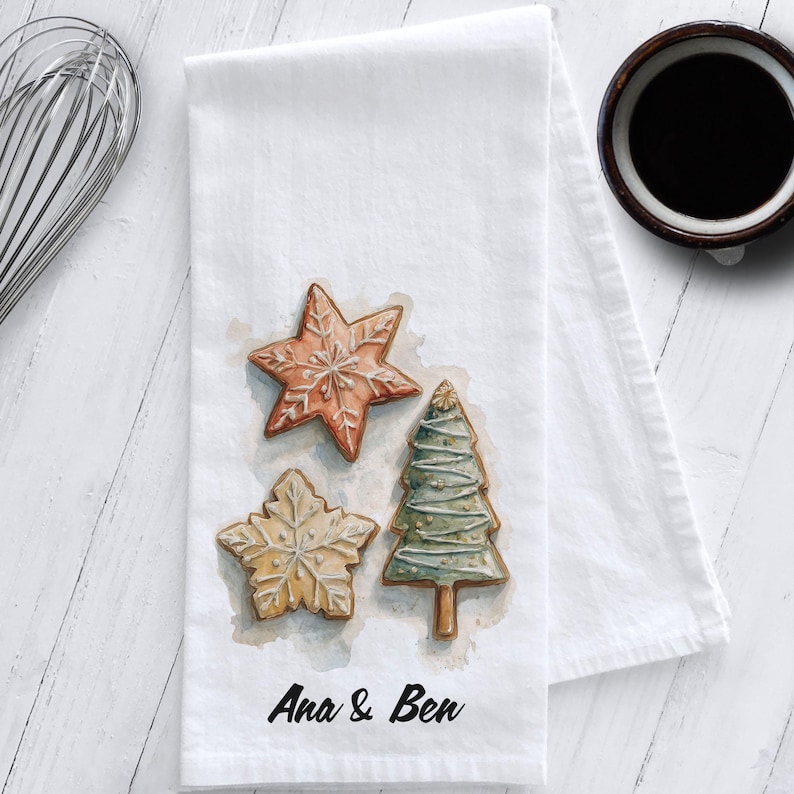 White cotton flour sack tea towel featuring watercolor art of decorated Christmas cookies – star, snowflake, and Christmas tree