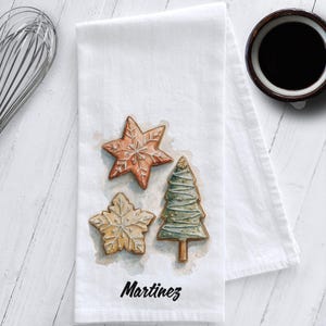 White cotton flour sack tea towel featuring watercolor art of decorated Christmas cookies – star, snowflake, and Christmas tree