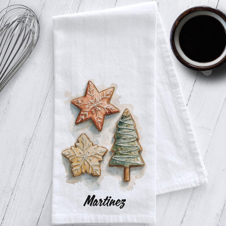 White cotton flour sack tea towel featuring watercolor art of decorated Christmas cookies – star, snowflake, and Christmas tree