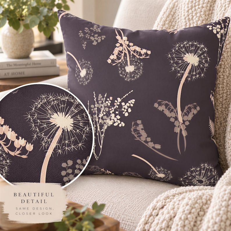 a decorative pillow with a floral pattern on a dark background. The pillow is placed on a couch, and there is a plant in the background.